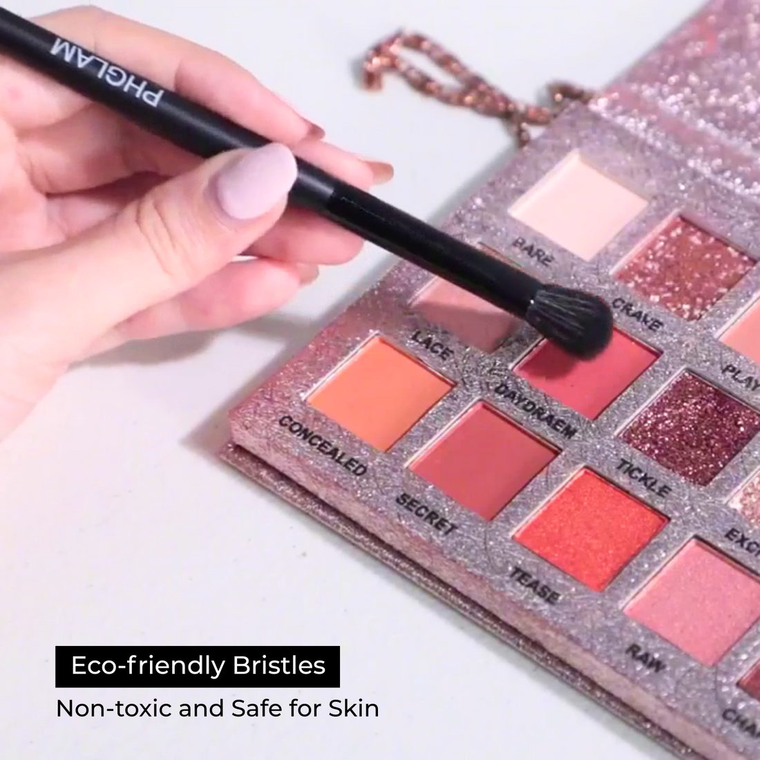 Makeup brush with eco-friendly bristles over a makeup palette on a light background