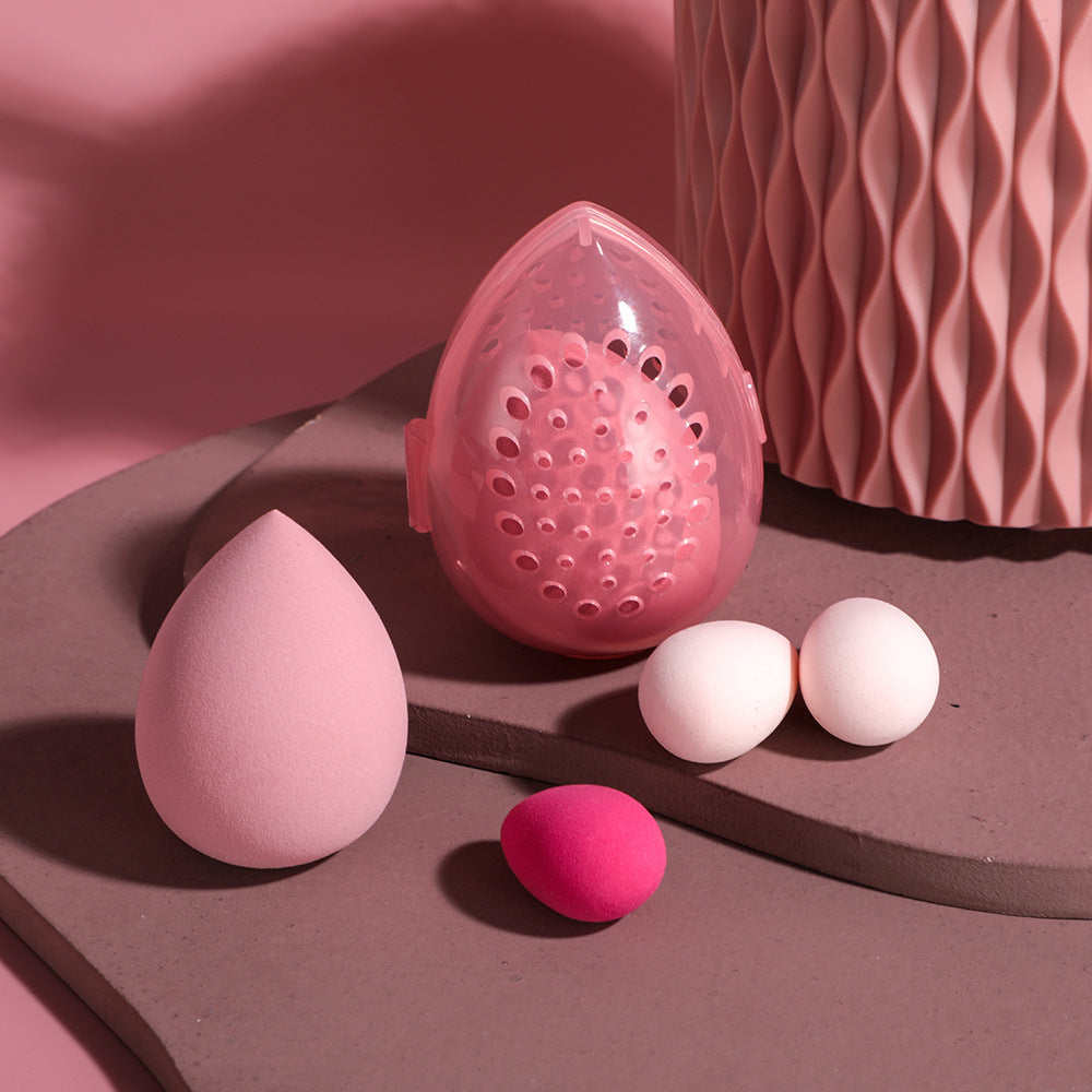 Pink makeup sponge and applicators on a brown surface with a pink textured background