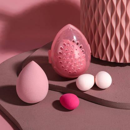 Pink makeup sponge and applicators on a brown surface with a pink textured background